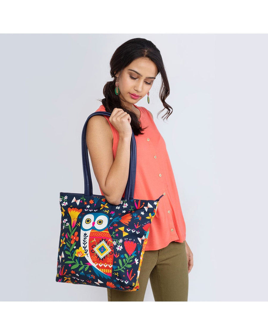 Woman wearing coral sleeveless top holding colorful owl print tote bag on shoulder