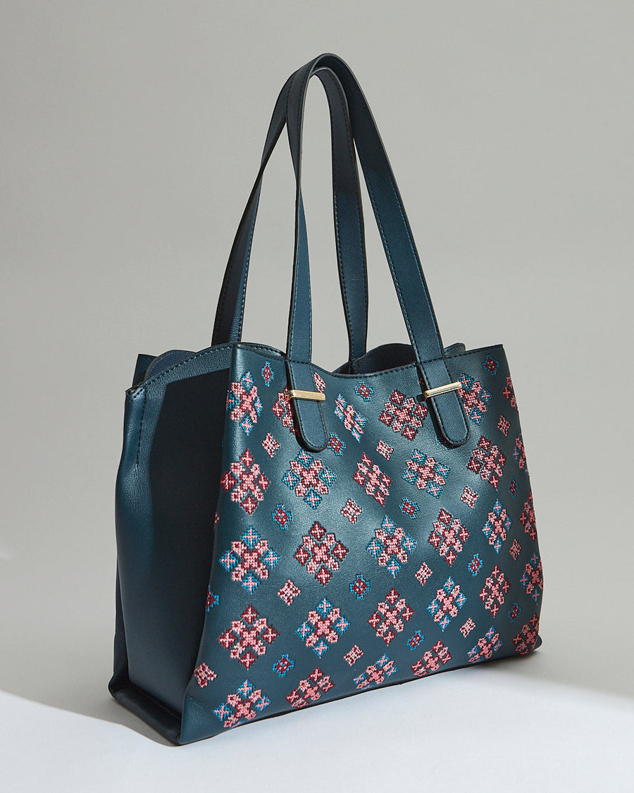 Side angle shot showing the depth and structure of the embroidered vegan leather tote bag