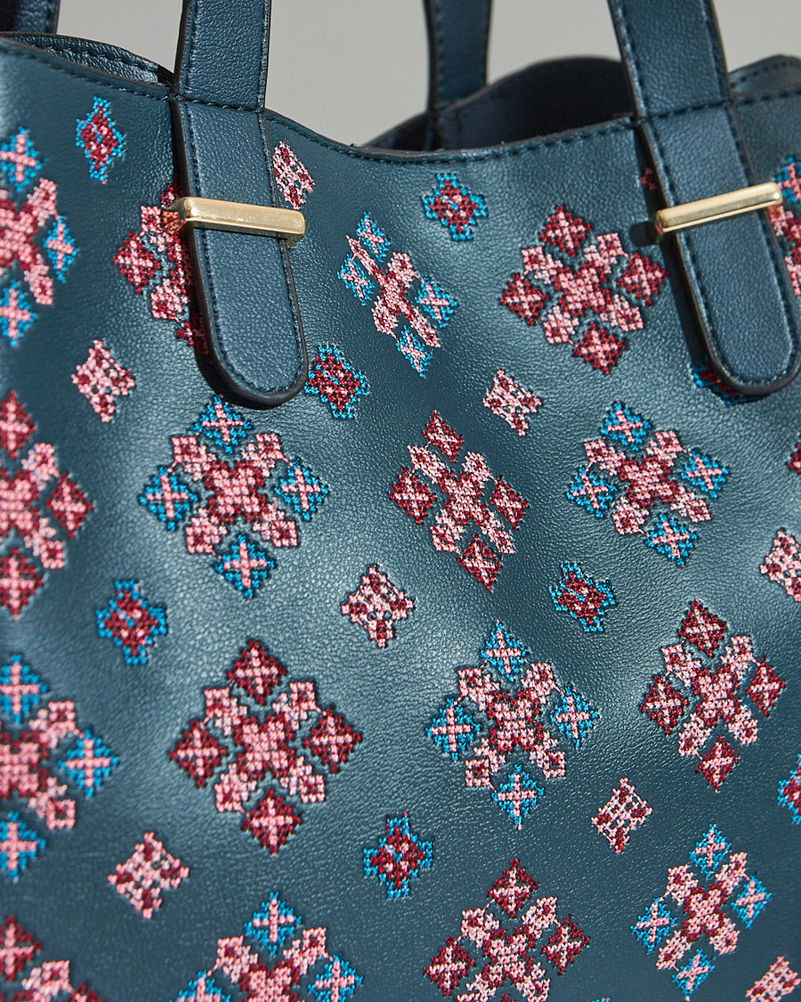 Close-up detail of the colorful embroidery and gold-tone hardware on the vegan leather tote bag