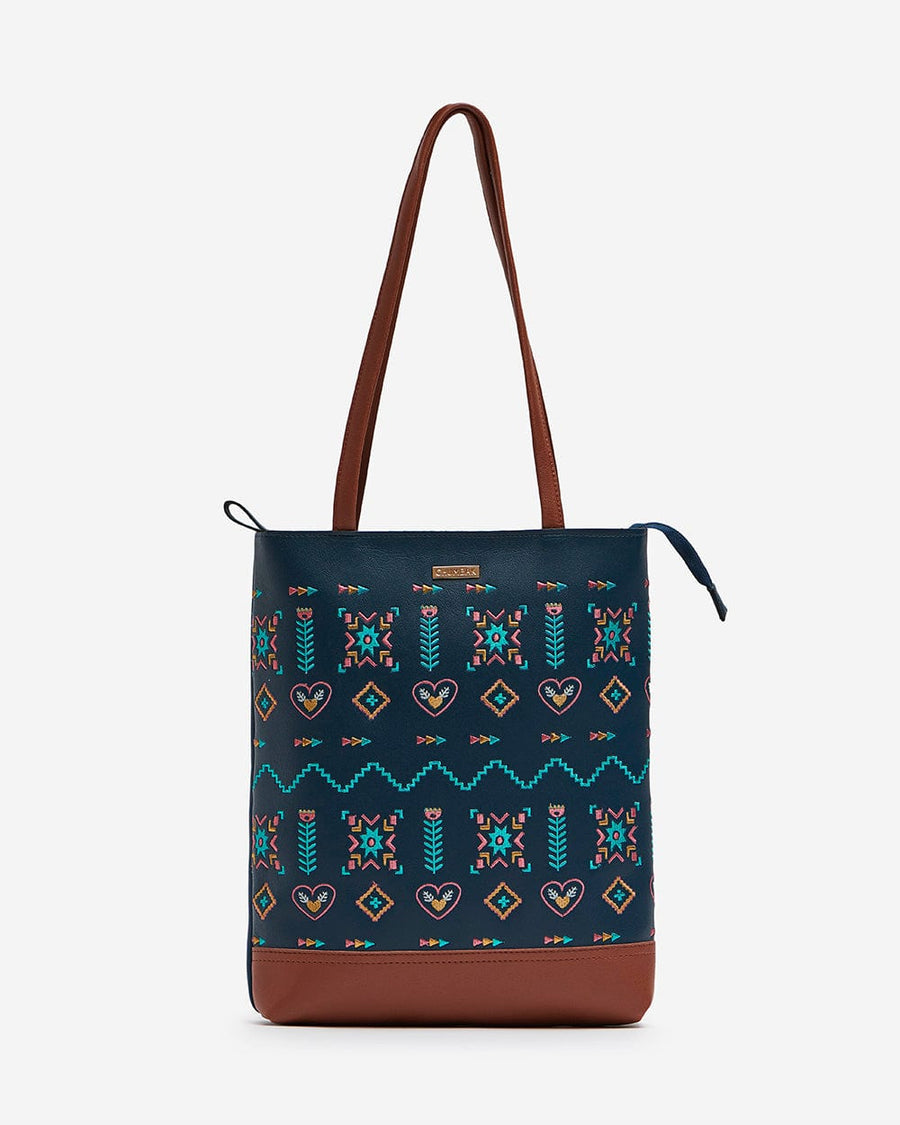 Front view of navy blue tote bag with multicolor aztec embroidery and brown faux leather base and straps