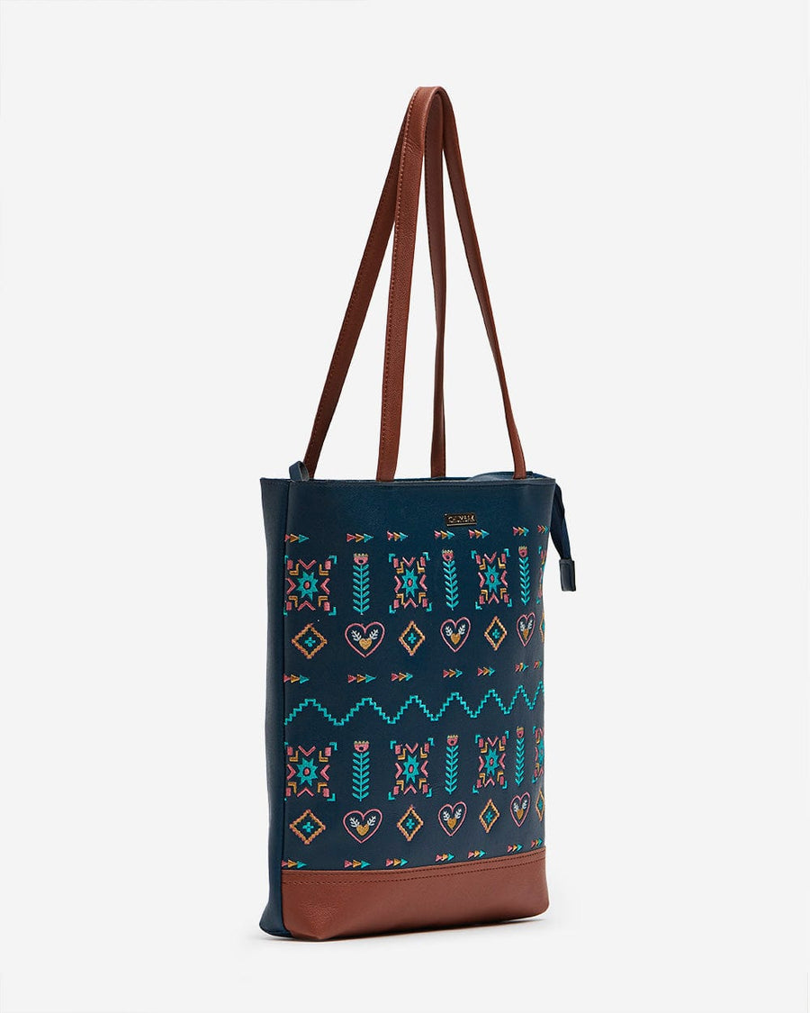 Side angle of navy embroidered tote bag showing thin brown shoulder straps and zip-top closure