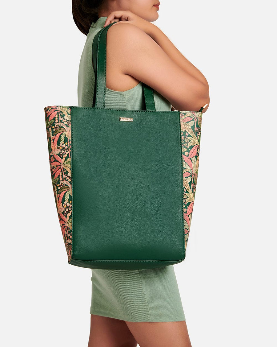 Woman in green dress carrying Palm Springs tote bag featuring solid green center and tropical floral print sides