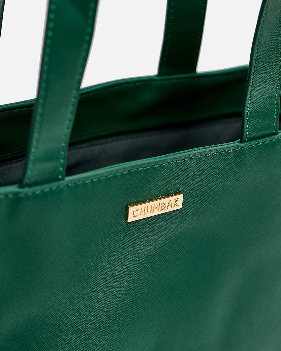 Close-up image of gold-tone metal logo plaque with 'CHUMBAK' embossed on the green textured surface of tote