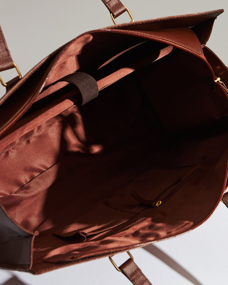 Floral patterned tote bag with annotated features including vegan leather, laptop compartment, zipper closure, and dimensions