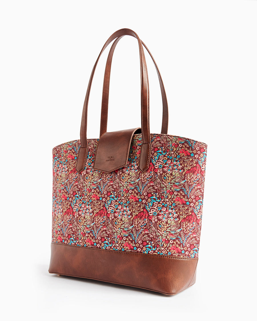 Angled side view of a floral tote bag showing brown leather handles and detailed botanical print