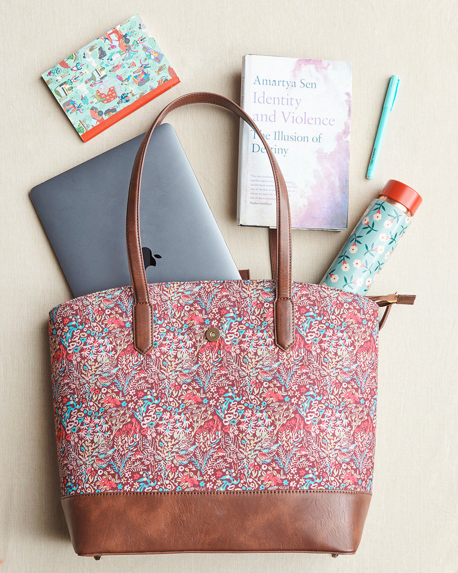 Styled image displaying the tote bag alongside a laptop, book, water bottle, pen, and journal on a beige surface