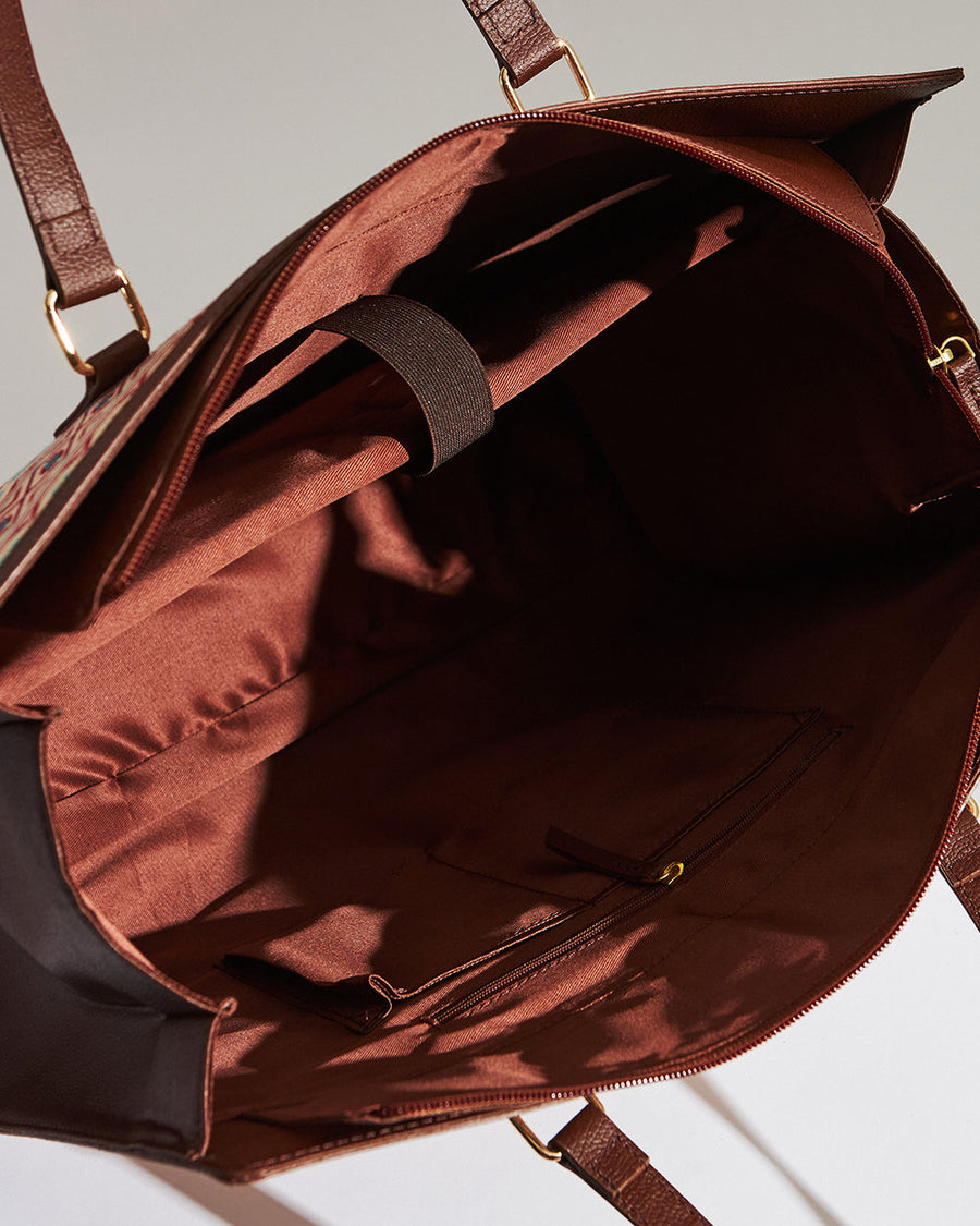 Photo annotating key features and measurements of the Aztec patterned tote including vegan leather, zipper closure, laptop compartment, width, depth, and length