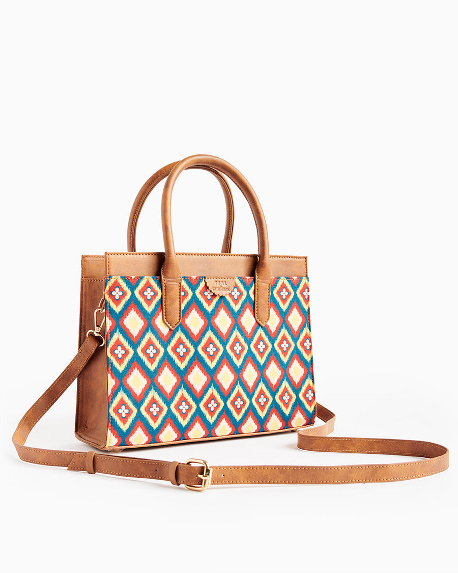 Tan leather handbag with colorful diamond and floral pattern and adjustable shoulder strap on white background