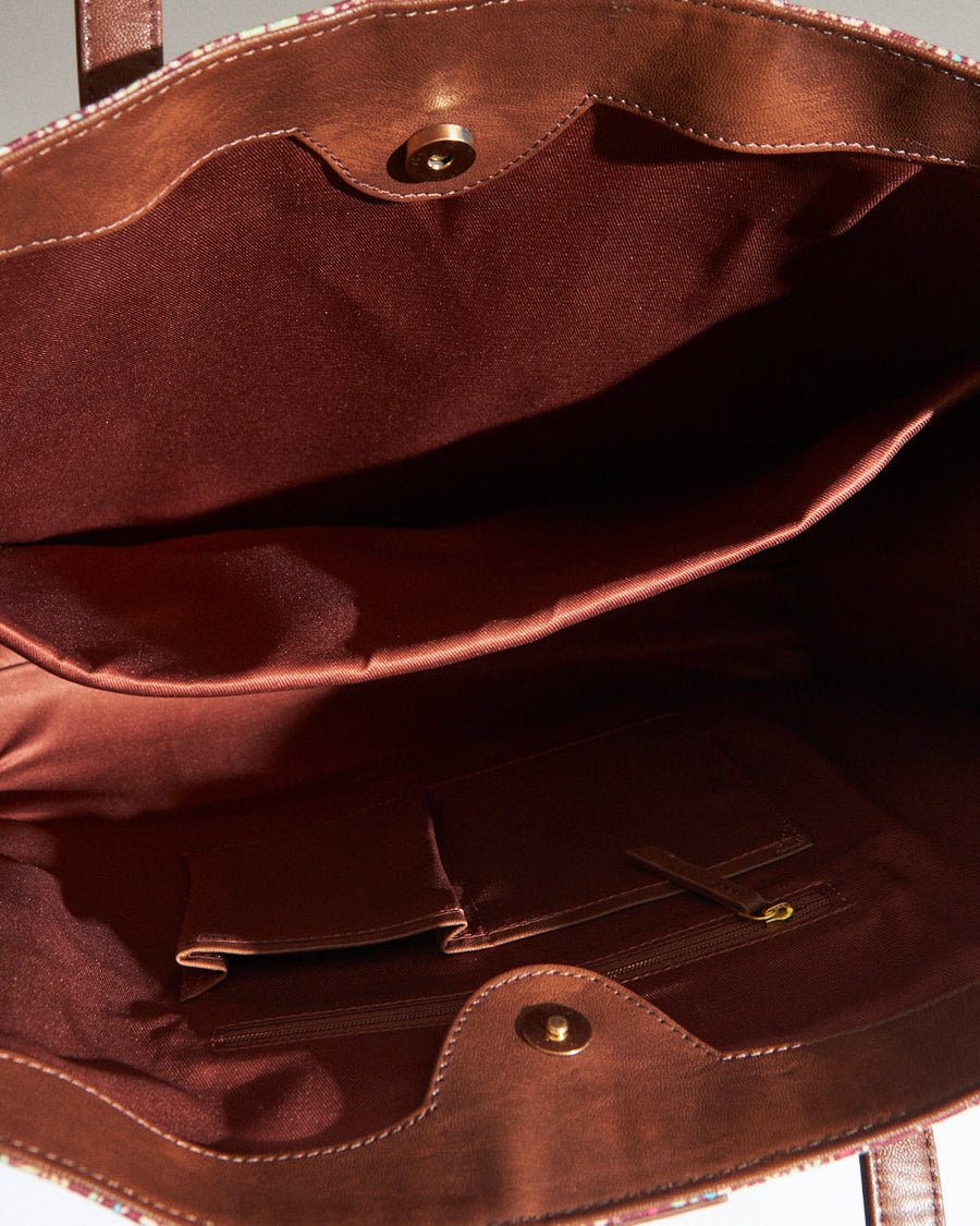Side angle showcasing the structured floral canvas tote bag with brown vegan leather sides and handles on a white surface
