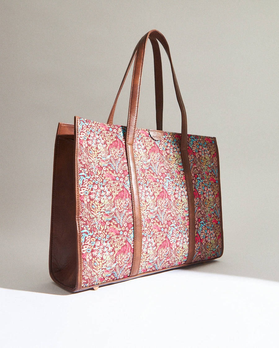 Close-up of tote bag exterior floral canvas print and brown vegan leather label embossed with Teal By Chumbak brand