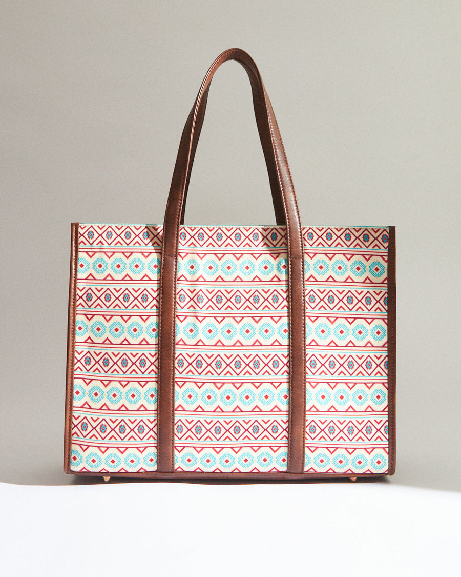Straight front view of the tote bag with geometric pattern, vegan leather straps, and base metal studs