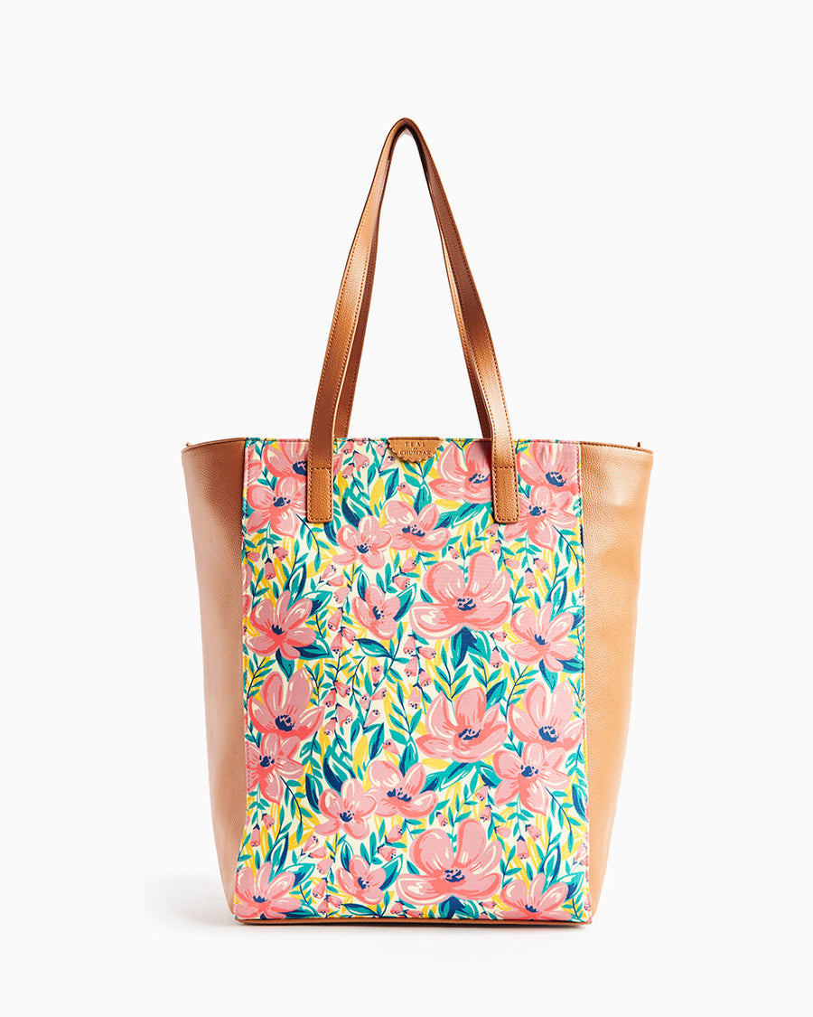 Front view of floral tote bag with pink flowers and tan faux leather handles and sides on plain white background