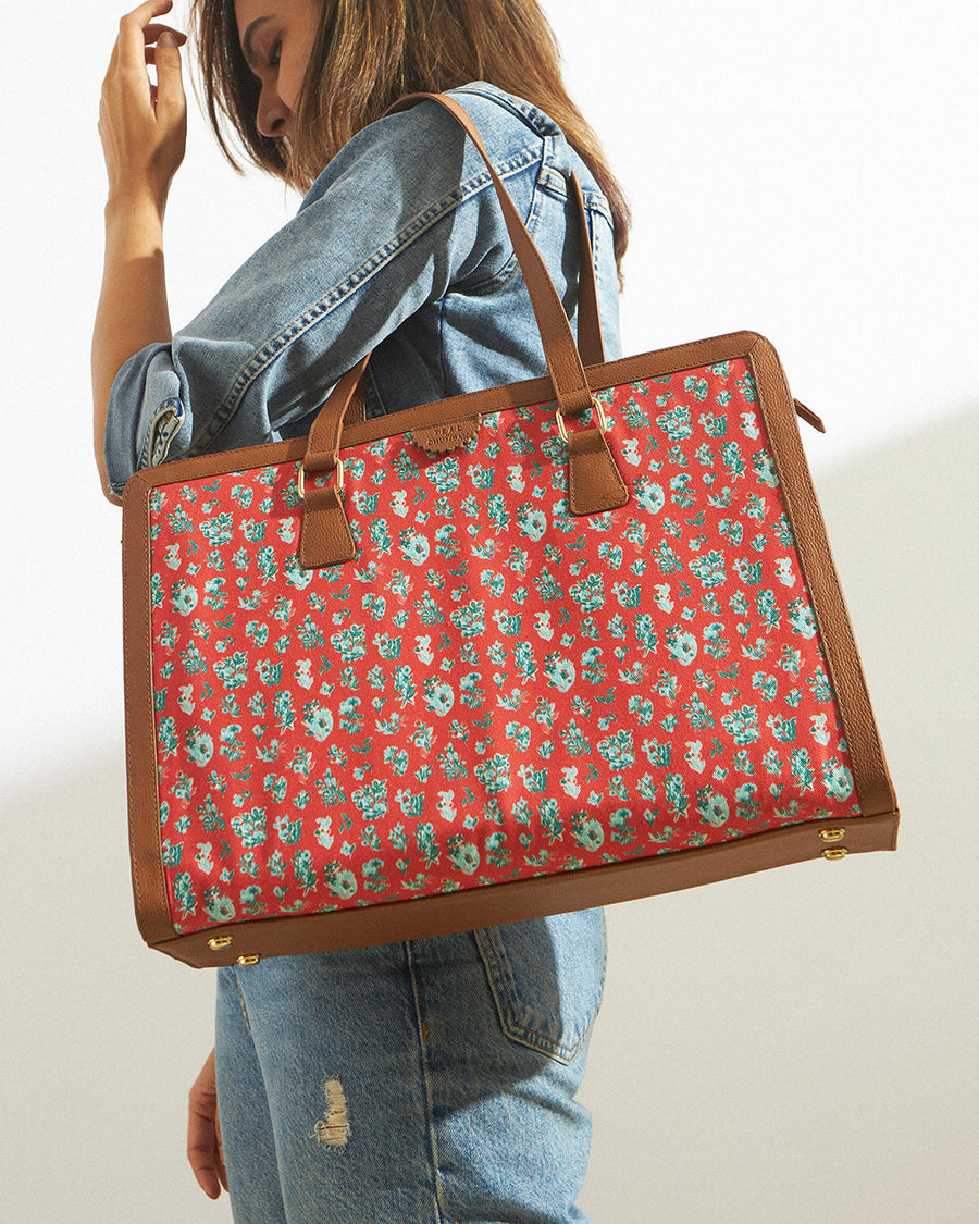 Woman wearing denim jacket carrying red floral wildflower tote bag with brown vegan leather handles on shoulder