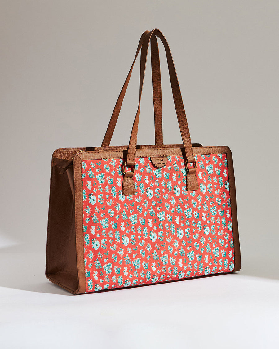 Angled side view of red floral canvas tote bag with brown vegan leather details and dual shoulder straps