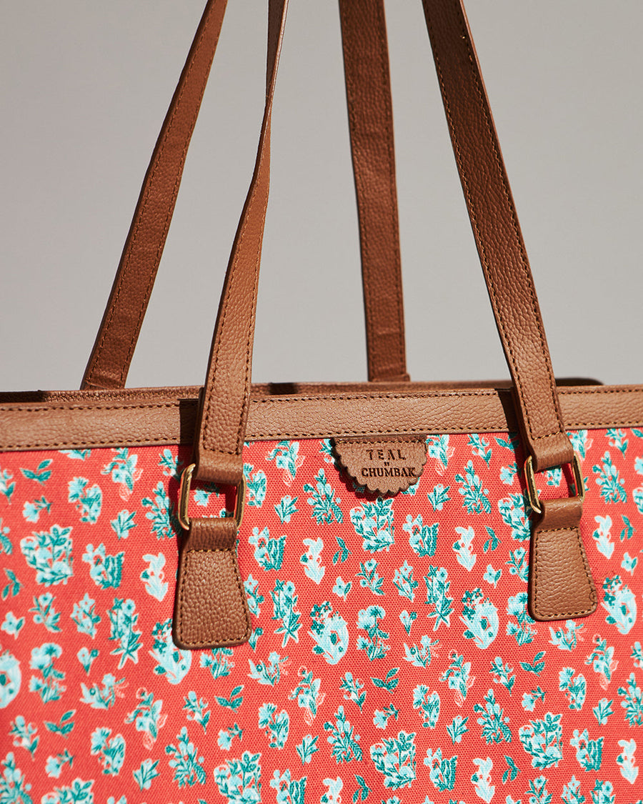 Close-up of tote bag upper section showing brown vegan leather straps attached by gold rings and wildflower canvas print