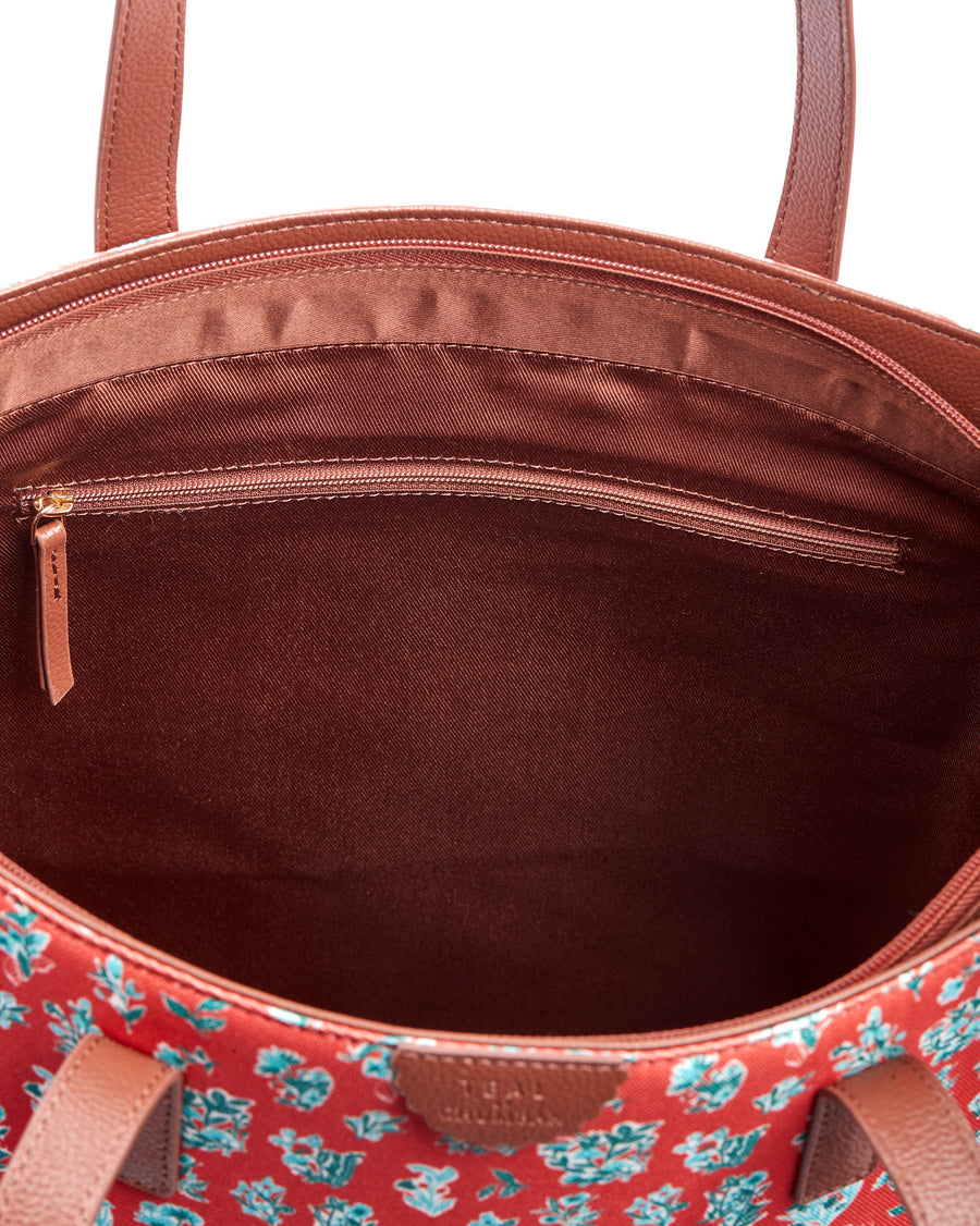 Top view of fully packed floral print tote bag with cosmetics, books, and accessories inside