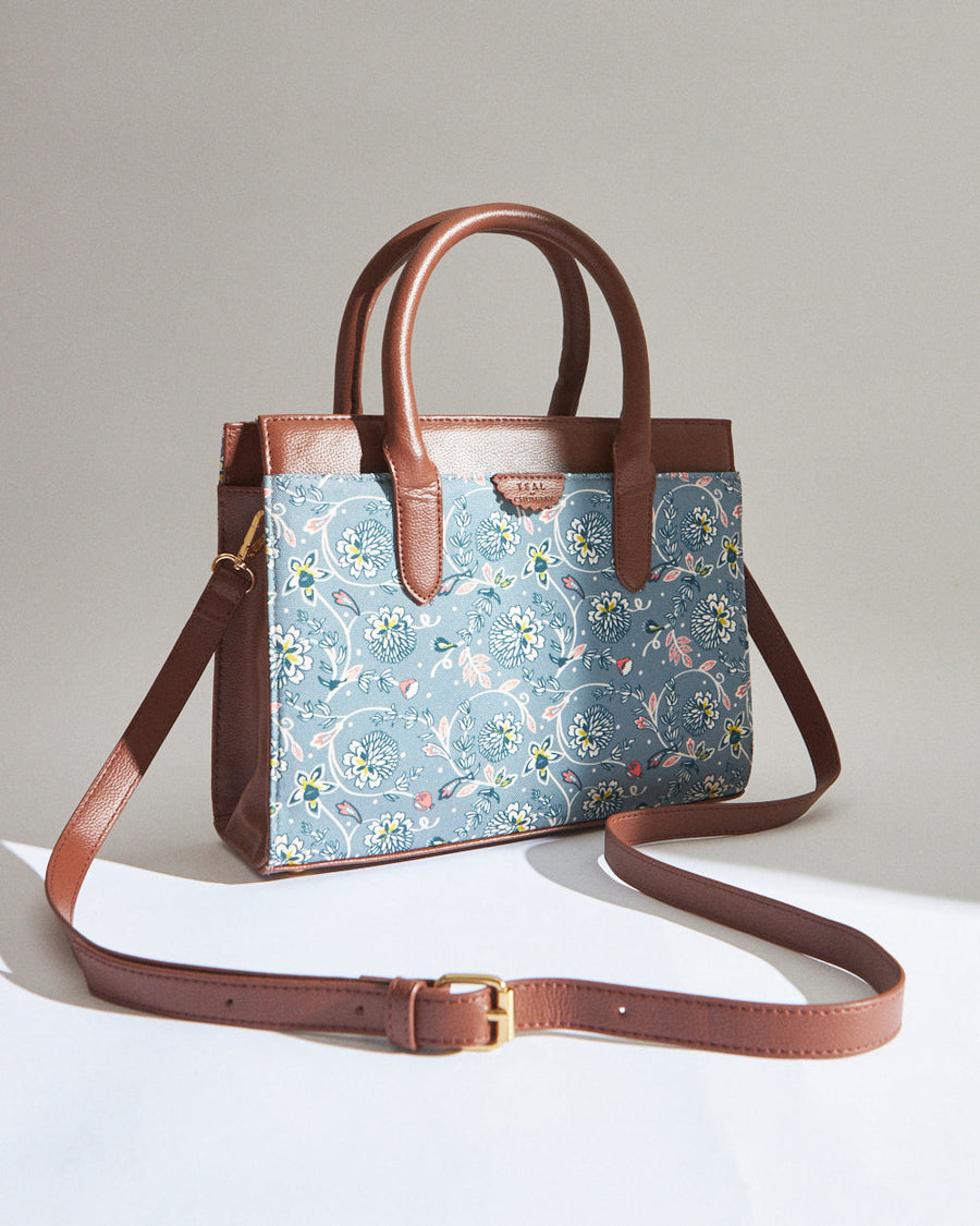 Teal floral canvas handbag with brown vegan leather handles and detachable adjustable shoulder strap on white background