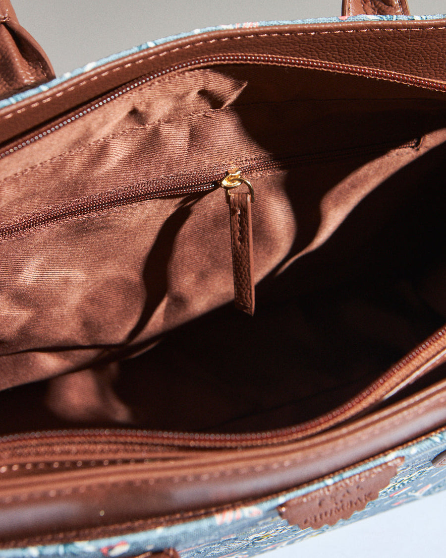 Interior close-up of teal floral canvas handbag showing spacious compartment with a zipped pocket