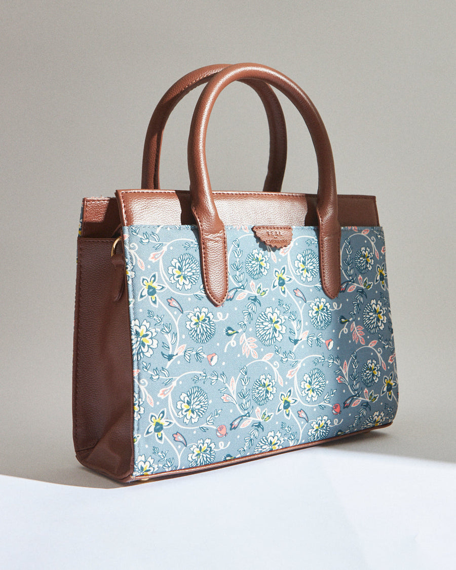 Side-angle view of the handbag, showcasing the floral canvas exterior and brown vegan leather details