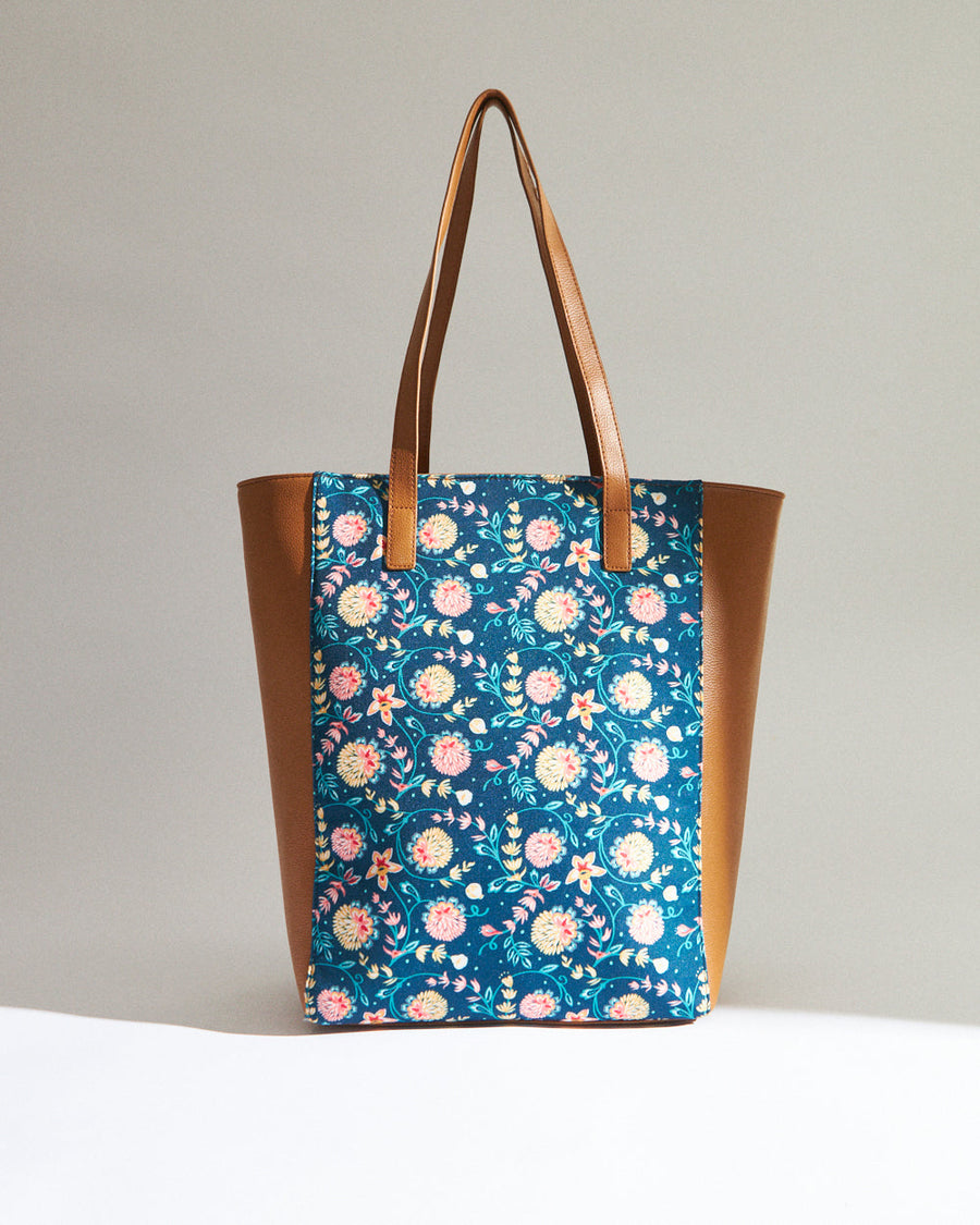 Woman with denim jacket holding floral print vegan leather tote bag with camel brown sides