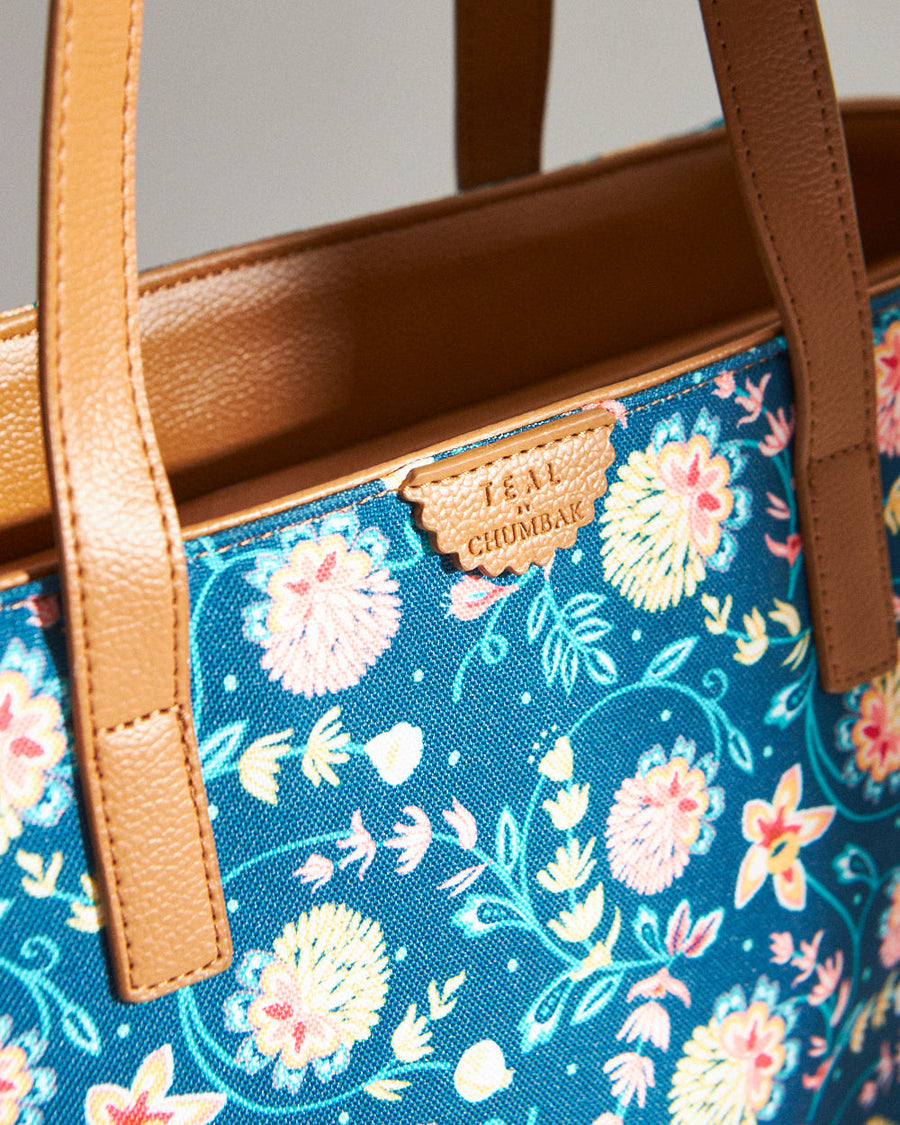 Close-up of tote bag floral canvas pattern and branded vegan leather label near handle