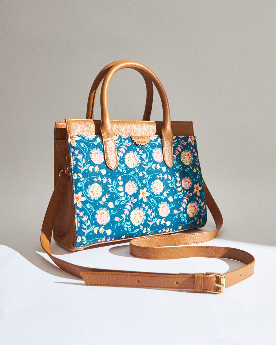 Light brown leather handbag with turquoise fabric highlighted by a colorful floral pattern and detachable strap