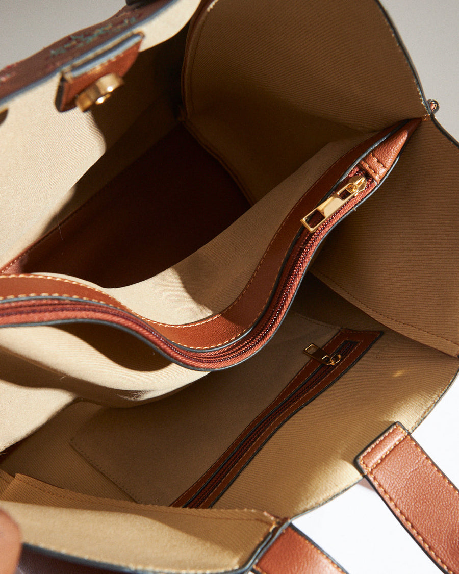 Close-up of the tote bag's cross stitch embroidery pattern in red, white, and blue tones on tan leather
