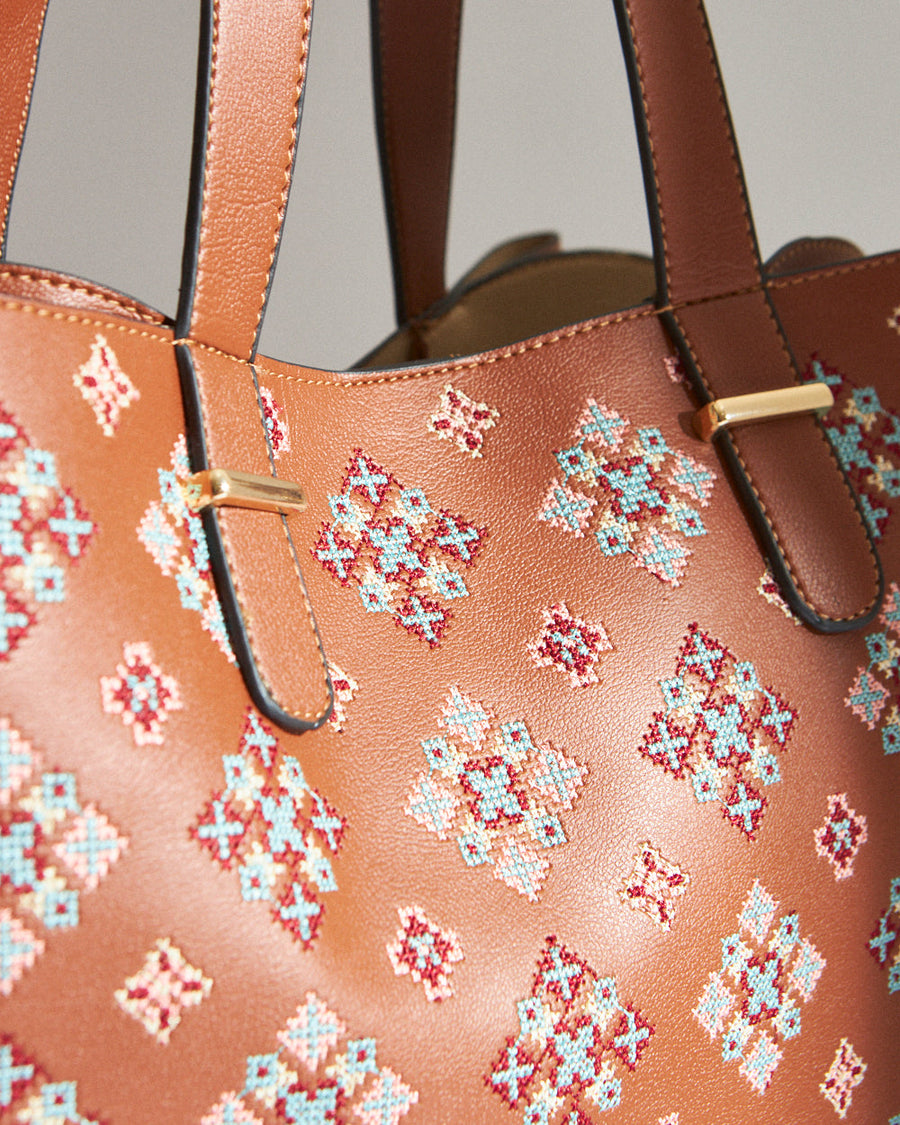 Detailed close-up of the bag's strap attachment with gold-tone hardware and precision stitching