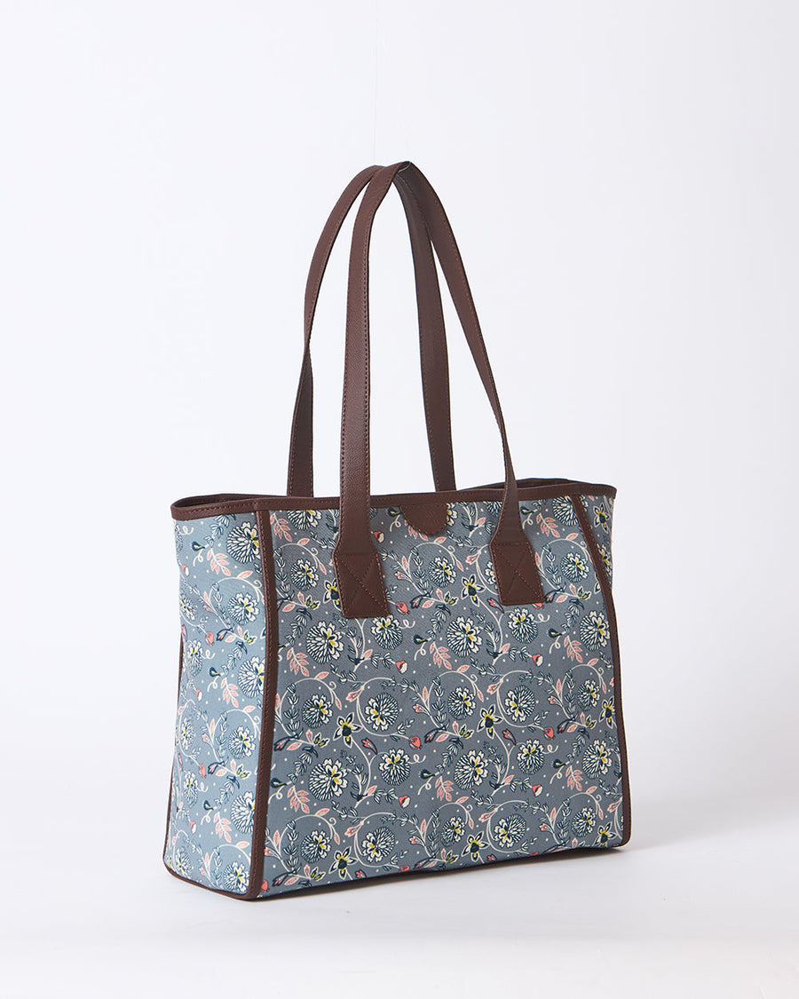 Elegant woman holding floral canvas tote bag near leg wearing denim jeans and cream shoes