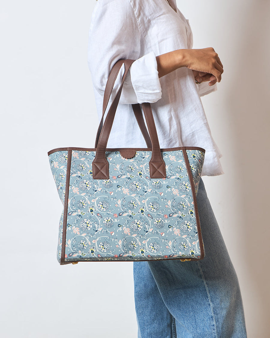 Woman carrying floral canvas tote bag over shoulder wearing white shirt and blue jeans