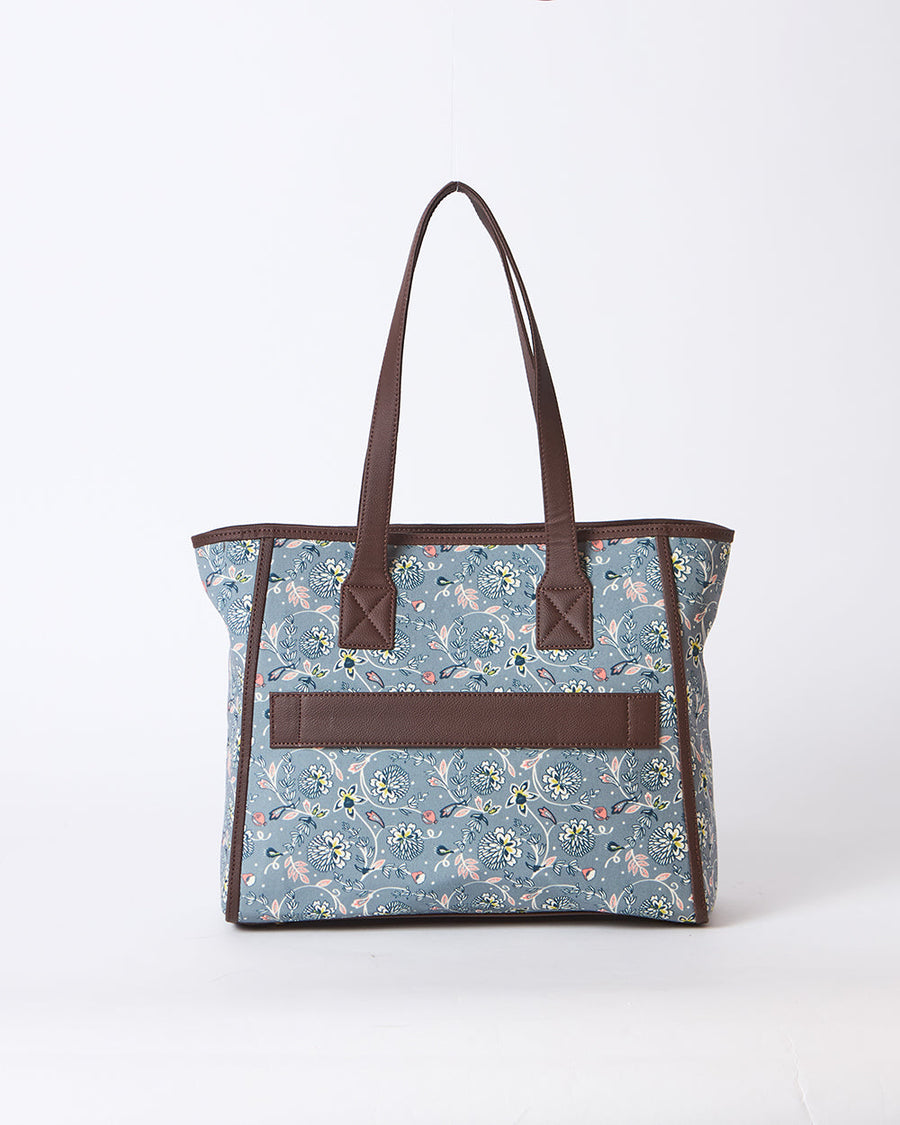 Back view of floral tote bag showing trolley sleeve in brown faux leather