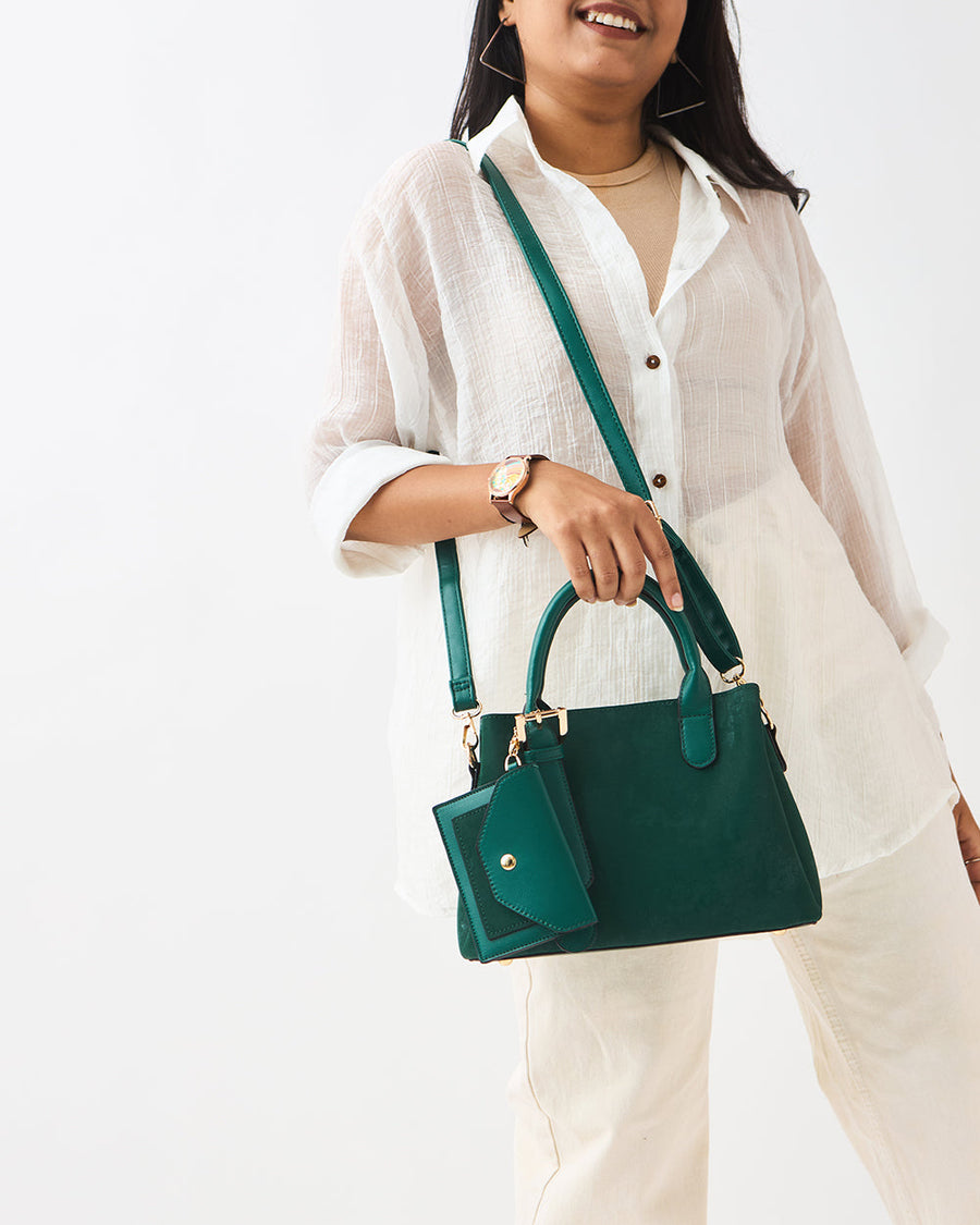 Woman wearing white textured blouse holding emerald green handbag with detachable mini pouch and shoulder strap