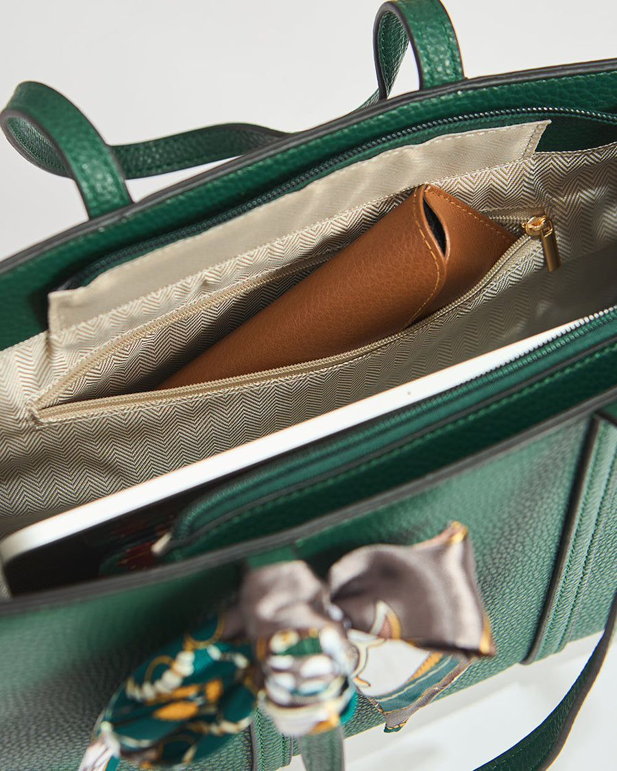 Close-up of printed scarf tied in a bow on the handle of green mini tote bag