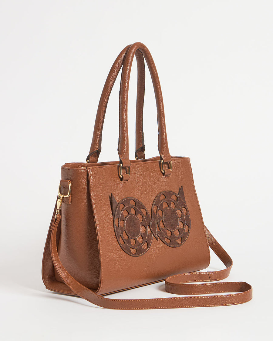 Close-up angled view of the brown owl motif handbag with handles upright and sling strap laid out.