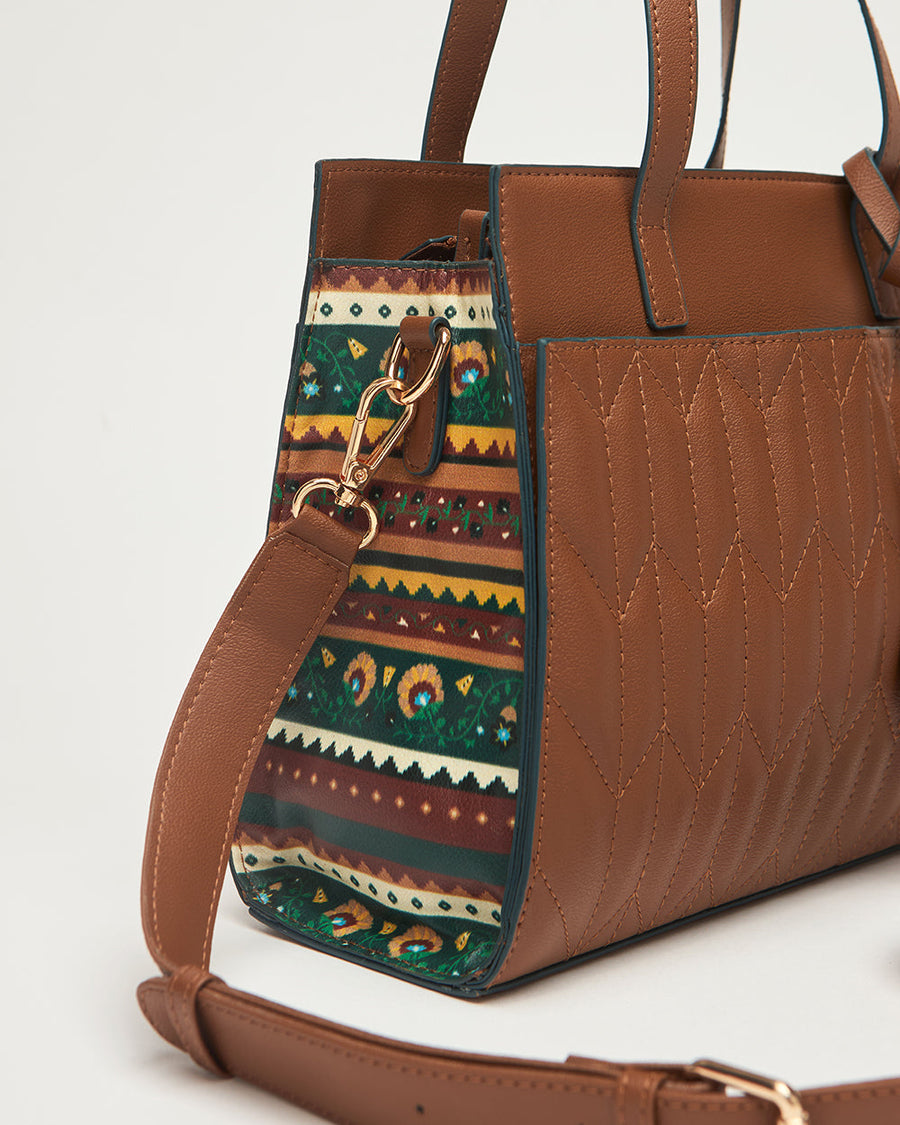 Side profile of handbag showing brown vegan leather body with ethnic patterned fabric panel