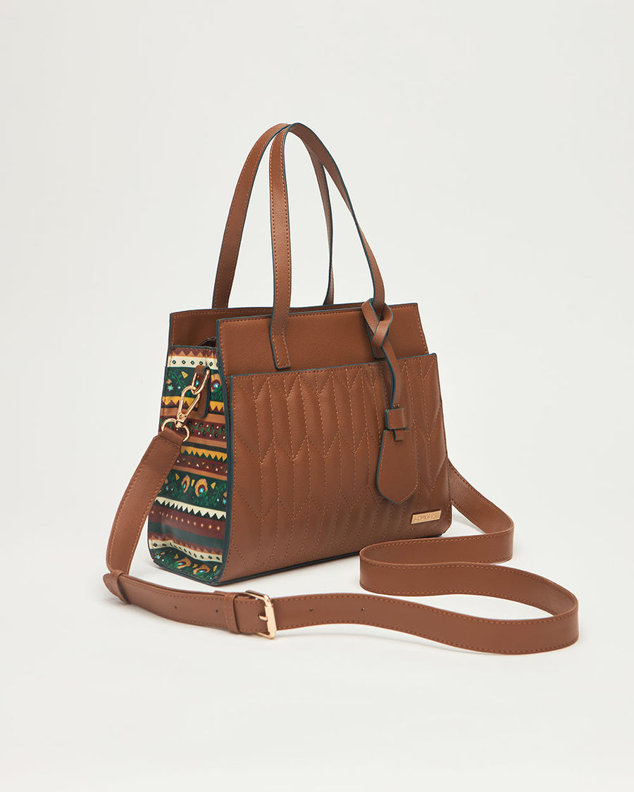 Brown vegan leather handbag with quilted front and patterned fabric side panels on white background