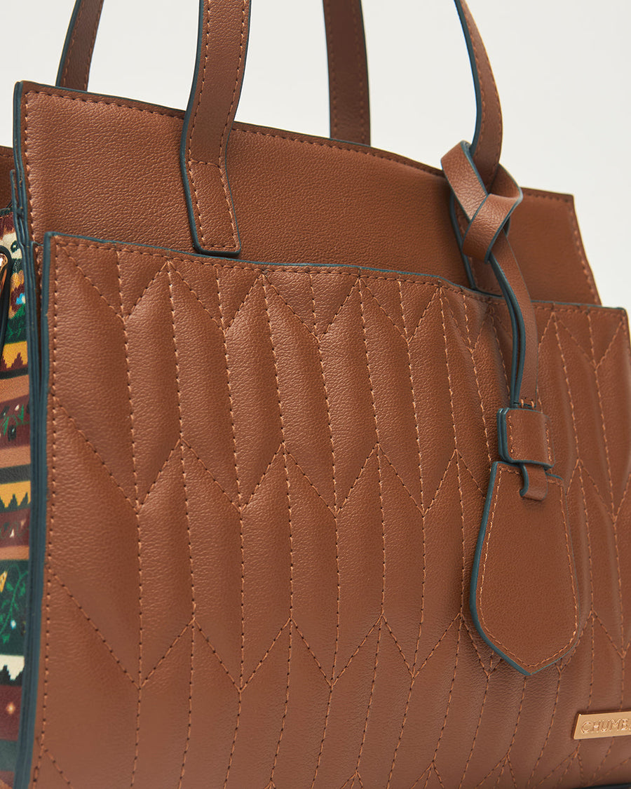 Close-up detail of quilted stitching pattern and leather accent tag on handbag front