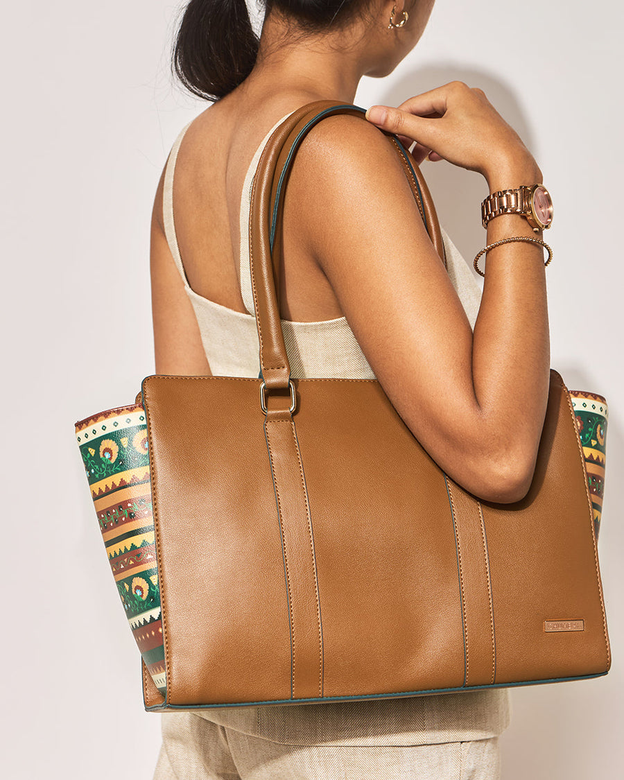 Woman carrying Kenya Tote bag on shoulder, highlighting the bag's structured form and floral side details
