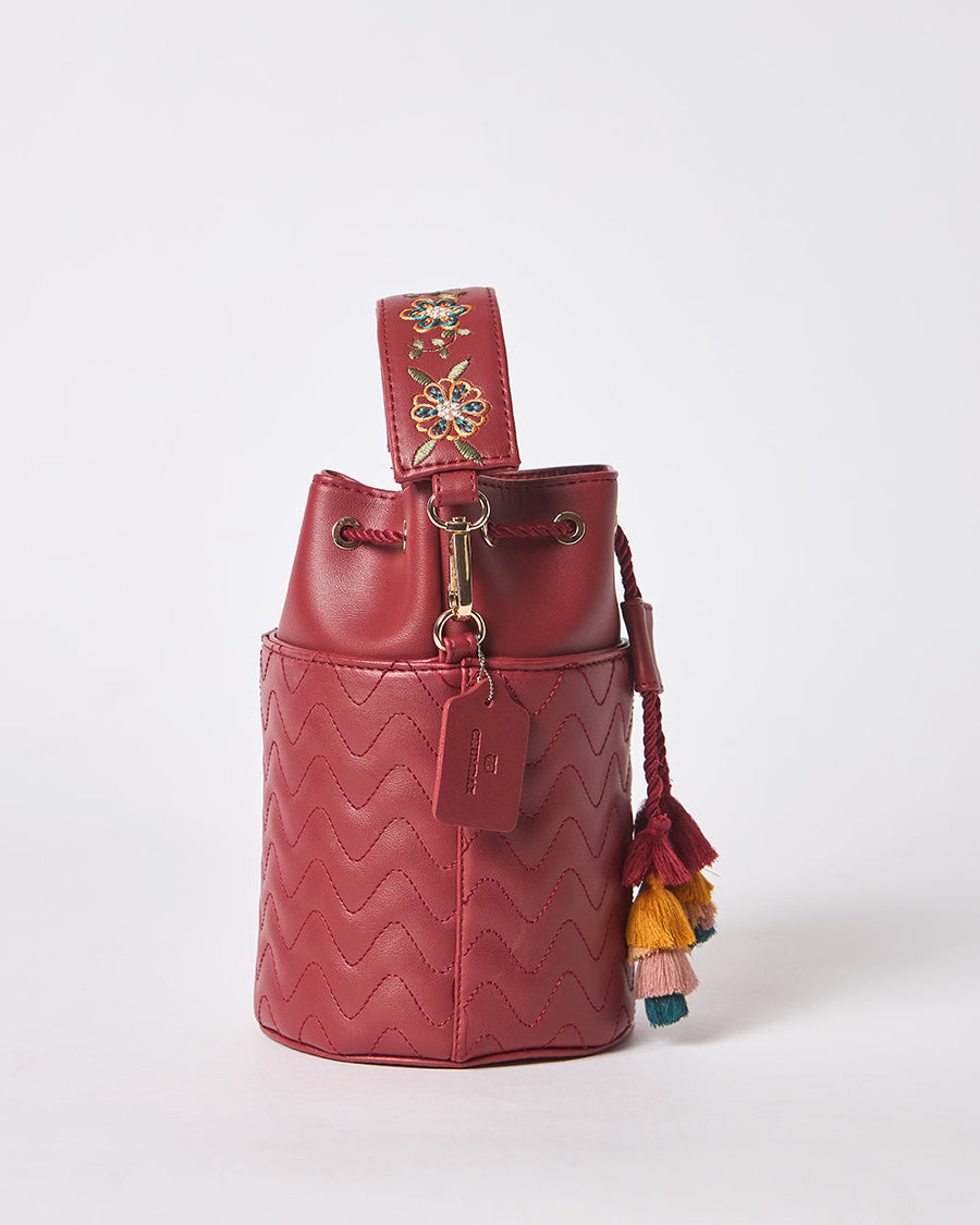 Side view of bucket bag showing drawstring closure, gold hardware, and hanging tag