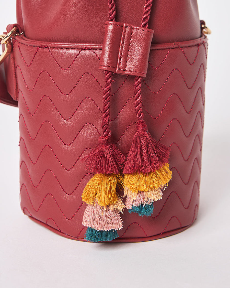 Close-up of multicolor tassels attached to the drawstring of embroidered red bucket bag