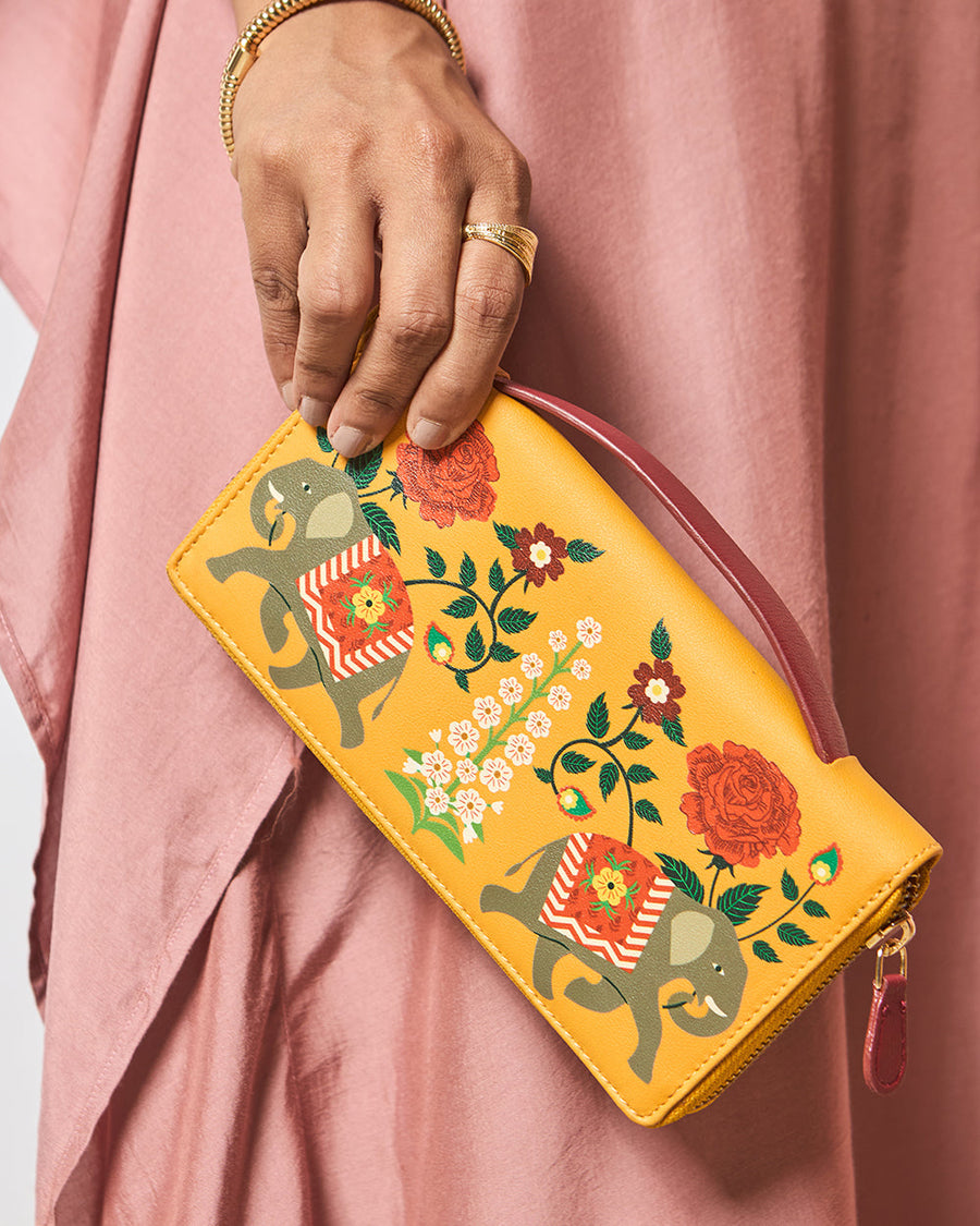 Woman showcasing mustard yellow elephant printed wallet with floral artwork and maroon handle