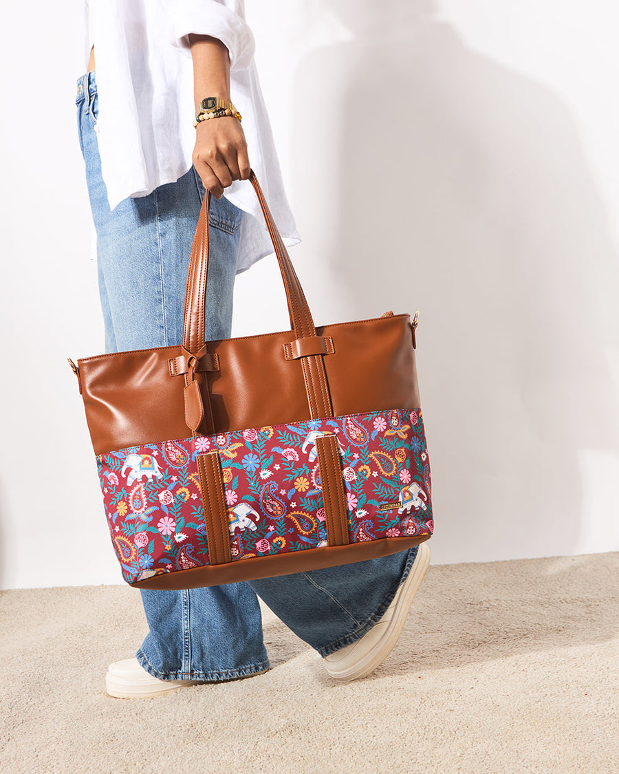 Close-up of woman holding the Paisley Tusker tote bag by its double handles showing detailed exterior print and bag shape