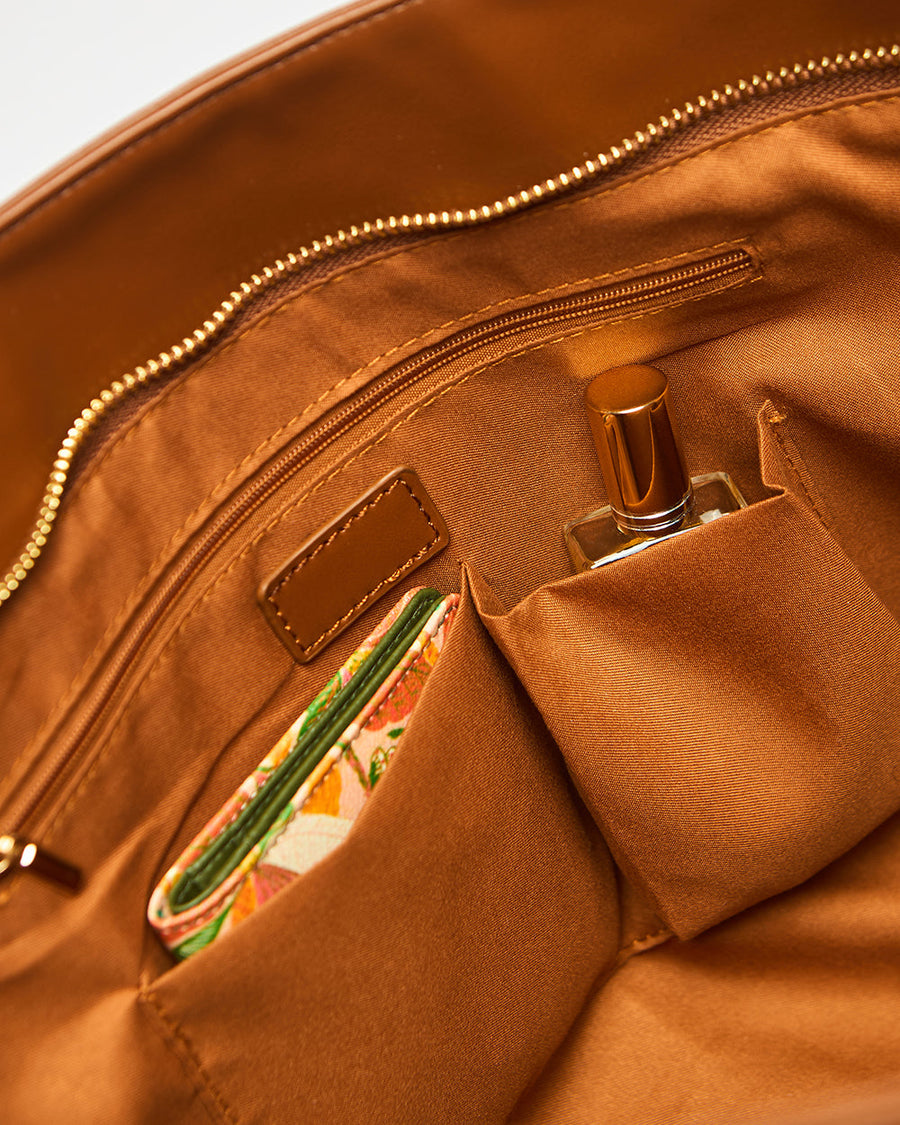 Interior view of tote bag showcasing organized pockets holding a wallet and perfume bottle