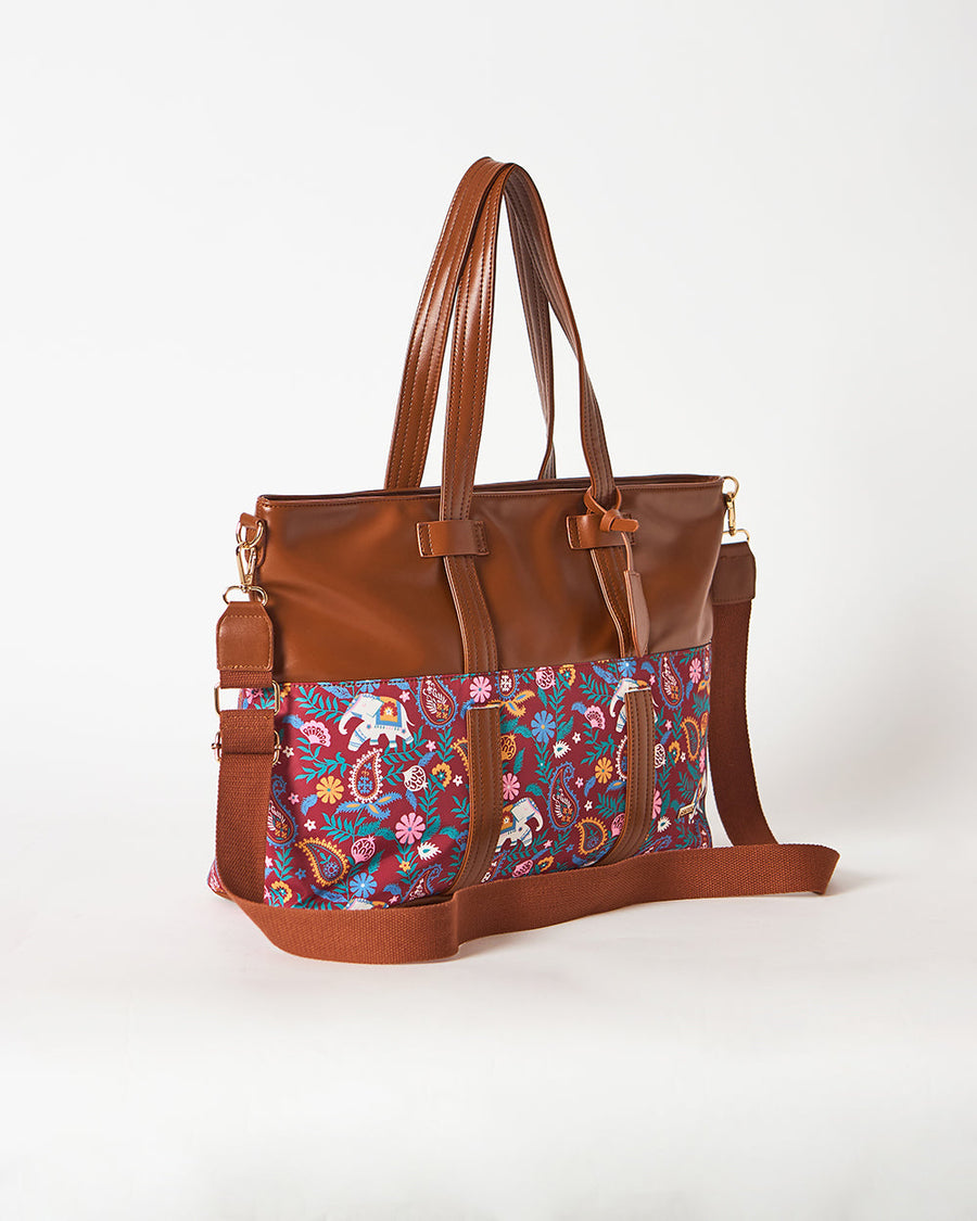 Detailed image of brown faux leather knot detail on the tote’s handle area with paisley and elephant textile below