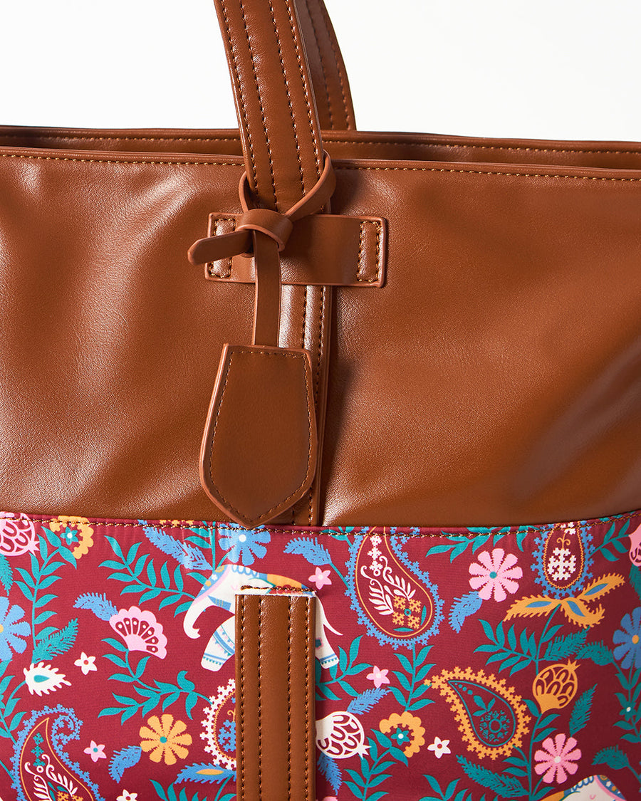 Side view of the Paisley Tusker tote bag with detached shoulder strap laid next to it