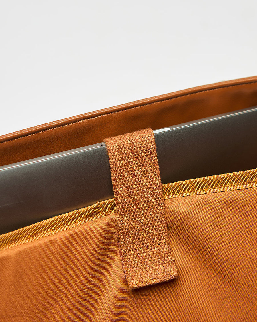 Detailed image of the paisley and elephant print fabric with metal brand logo on the front pocket area
