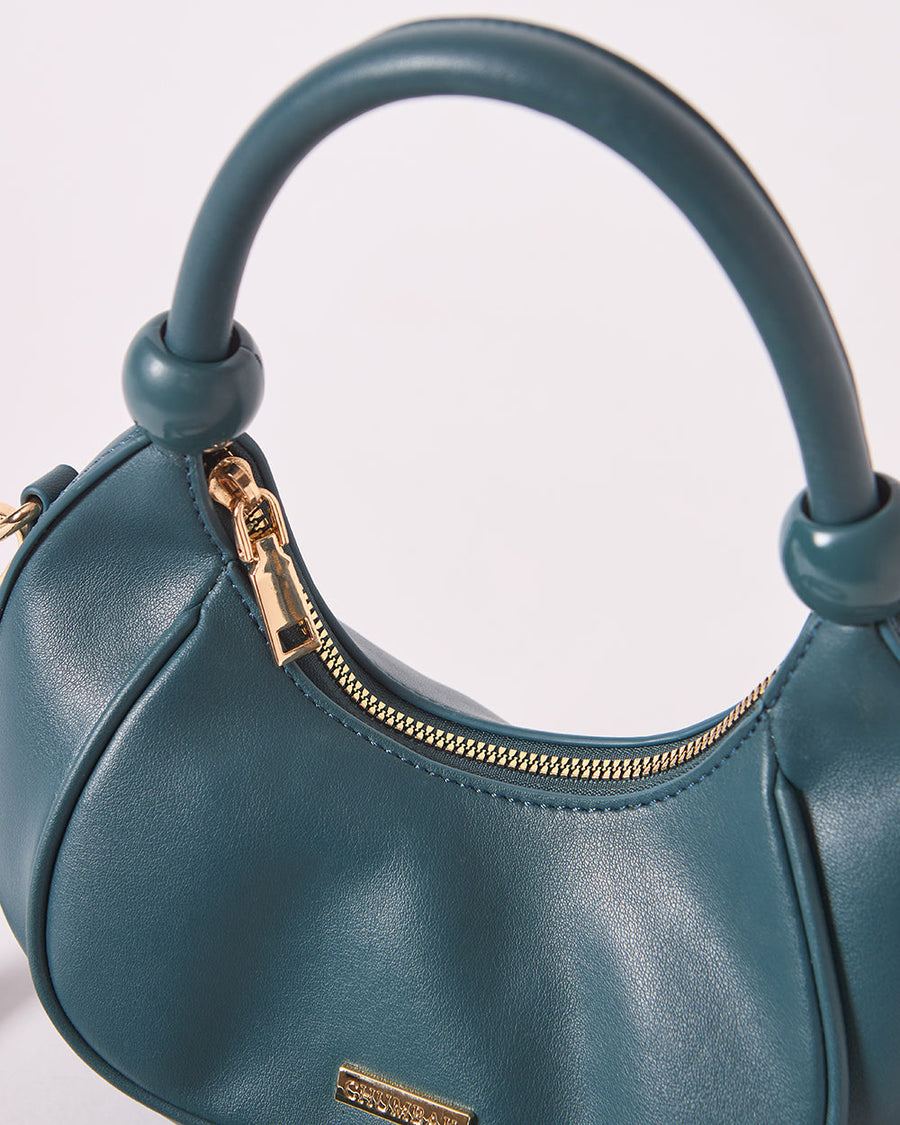 Close-up of gold zipper and smooth vegan leather of teal handbag