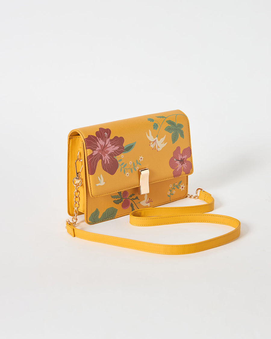 Mustard yellow floral shoulder bag on white background with detachable sling laid out neatly