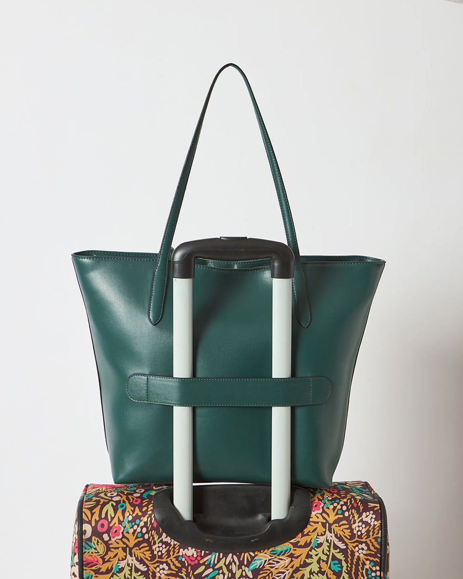 Side angle view of deep green vegan leather tote bag showing shape and embroidered leopard design