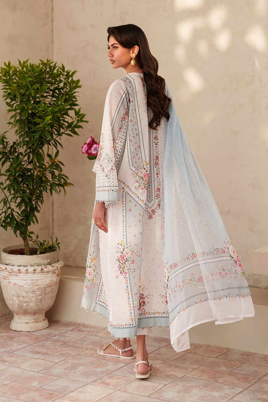 Back view of embroidered lawn suit with detailed floral embroidery and light printed dupatta flowing